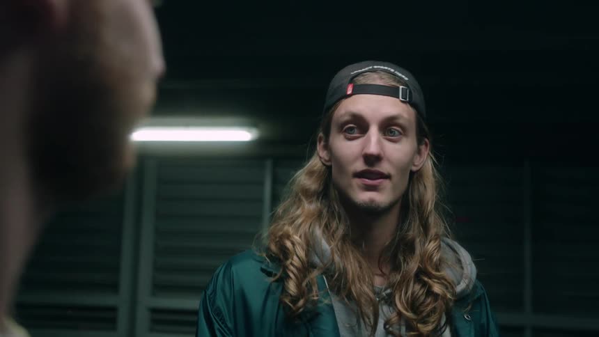 A man with long hair standing talking with a friend