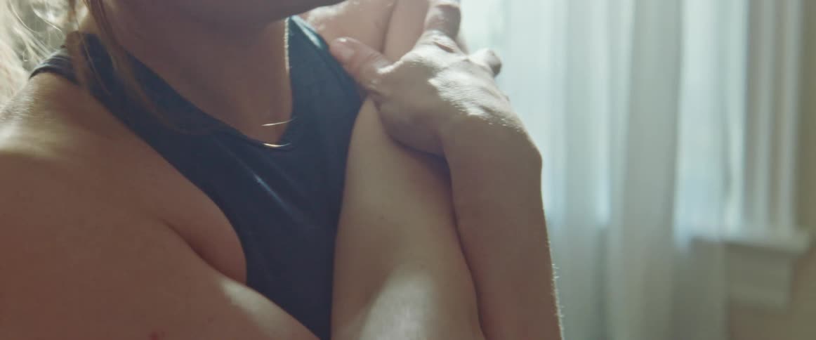 Pregnant woman with a ponytail warms up before working out in the living room at home