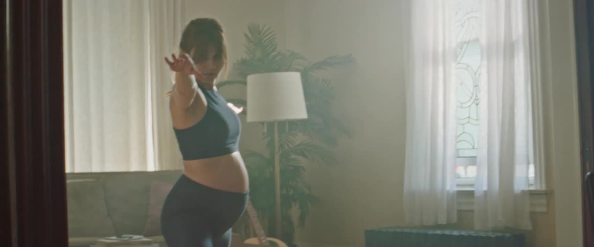 A pregnant woman is practicing yoga inside a home during the day