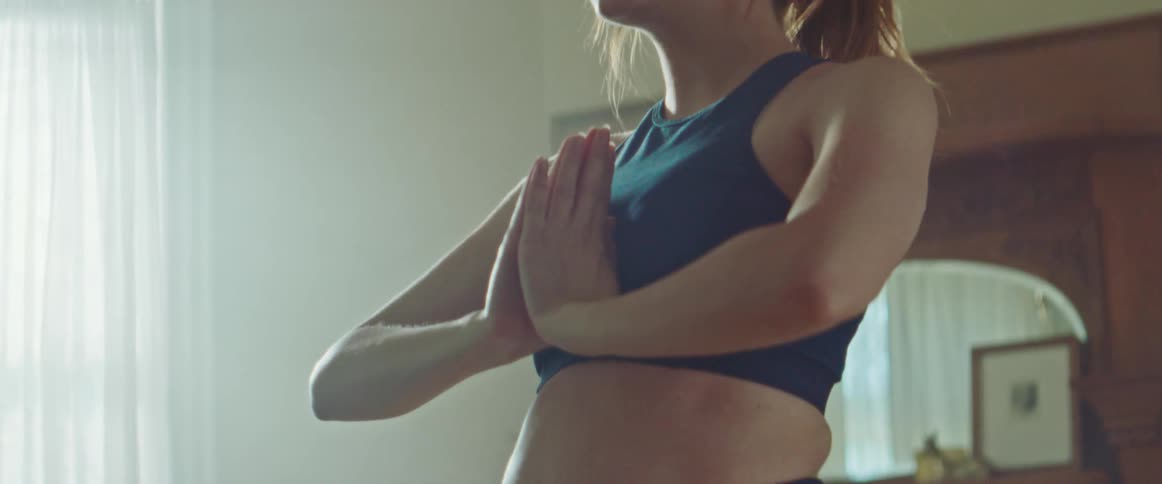 Pregnant woman with sport bra does yoga in the living room at home