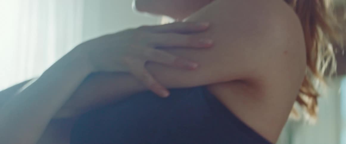 Pregnant woman with a ponytail and a sport top warms up in the living room at home