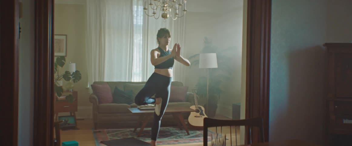 A woman is attempting to do yoga in the living room