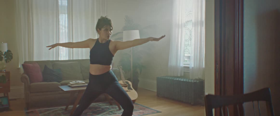 Pregnant woman with a ponytail warms up before working out in the living room at home