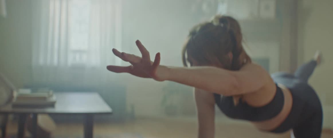 Pregnant woman with sport bra and leggings does stretching exercise on a pilates mat in the living room