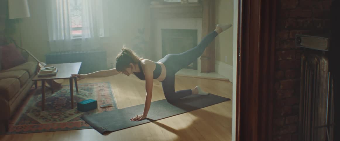 Pregnant woman does stretching exercise on a pilates mat in the living room at home