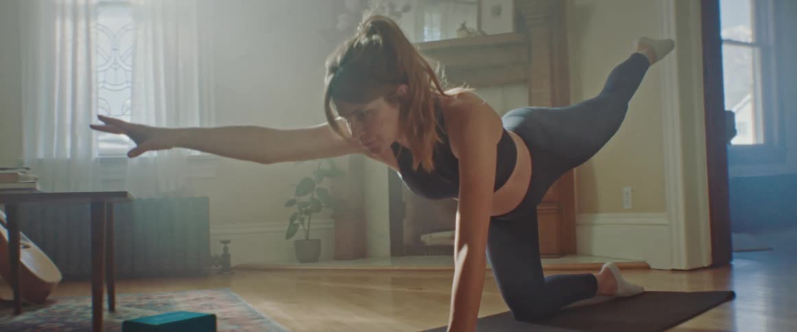 Pregnant woman does stretching exercise on a pilates mat in the living room at home