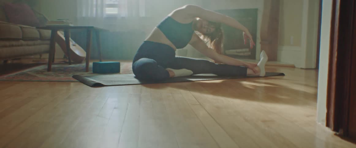 Woman with leggings and sport top does stretching in the living room at home