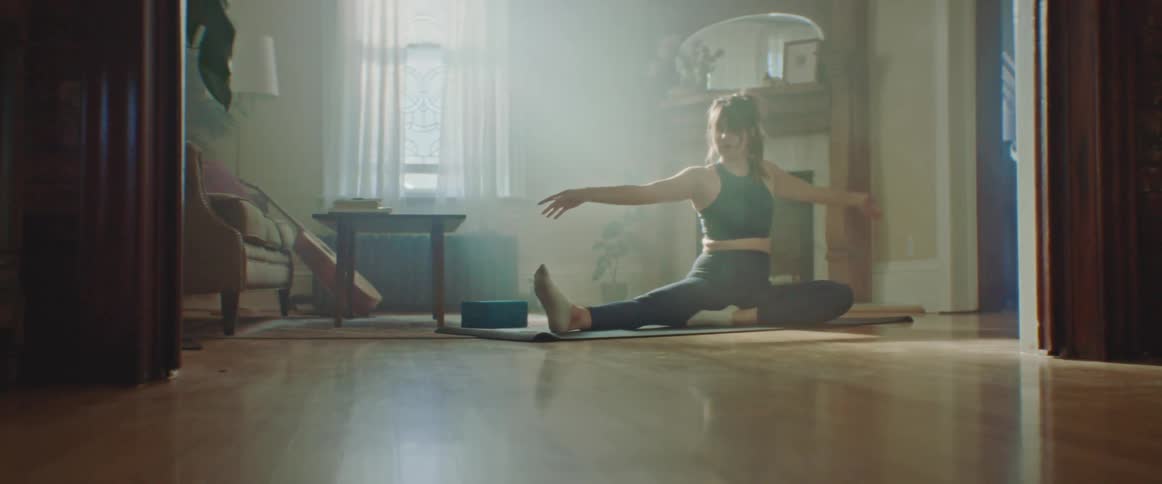 Pregnant woman with sport bra and leggings does stretching exercise on a pilates mat in the living room