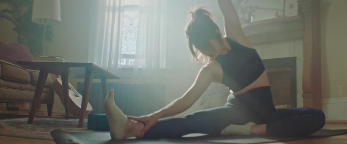 A woman is stretching indoors during the day