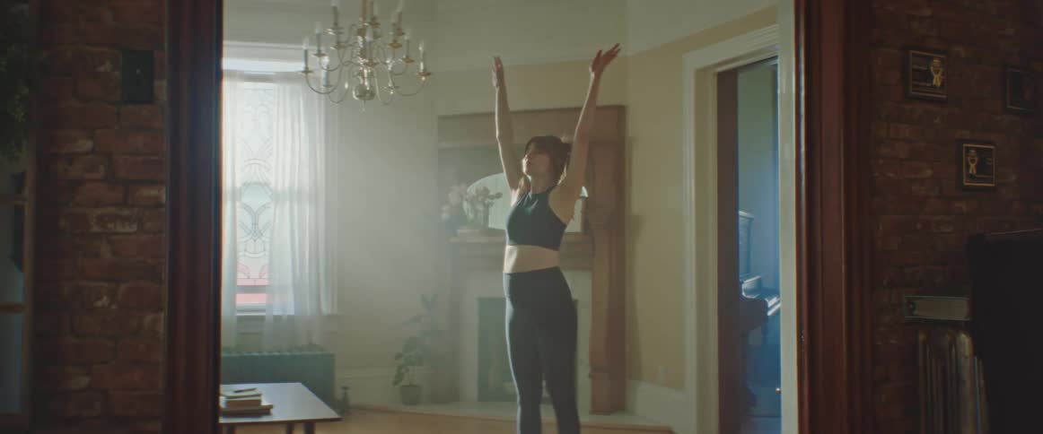 A woman does yoga on a yoga mat in her living room during the day