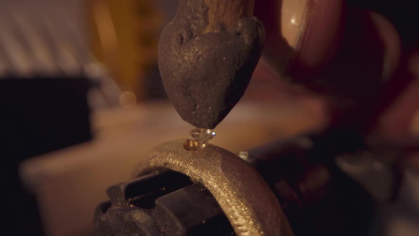 Jewelry maker insets diamond into golden piece of jewelry