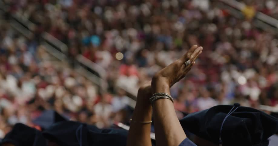 A person in a crowded stadium raising their hands up in the air