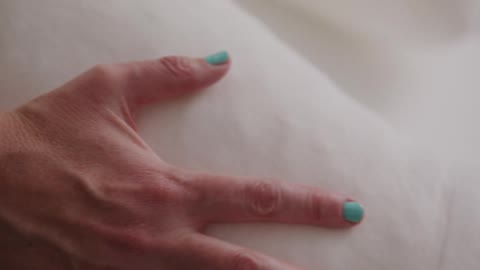 Hand of a woman feeling a soft white pillow