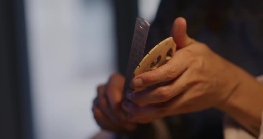 A person is carving a wooden object and scraping its surface with a tool