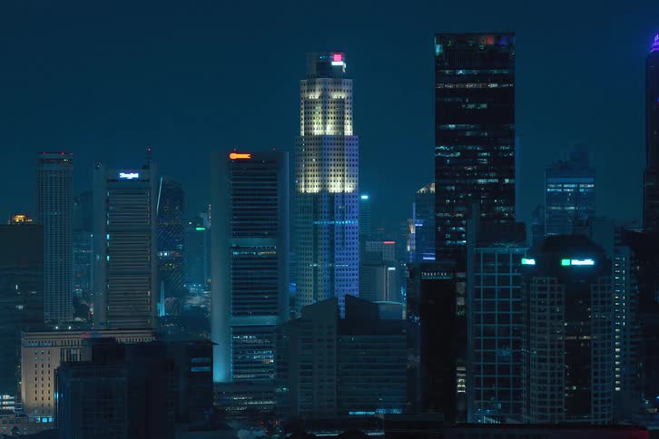 Skyline of skyscrapers in a metropolis with lights dimming and turning off at night in a timelapse