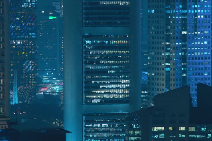 A region with several buildings and the lights in the apartments turn on