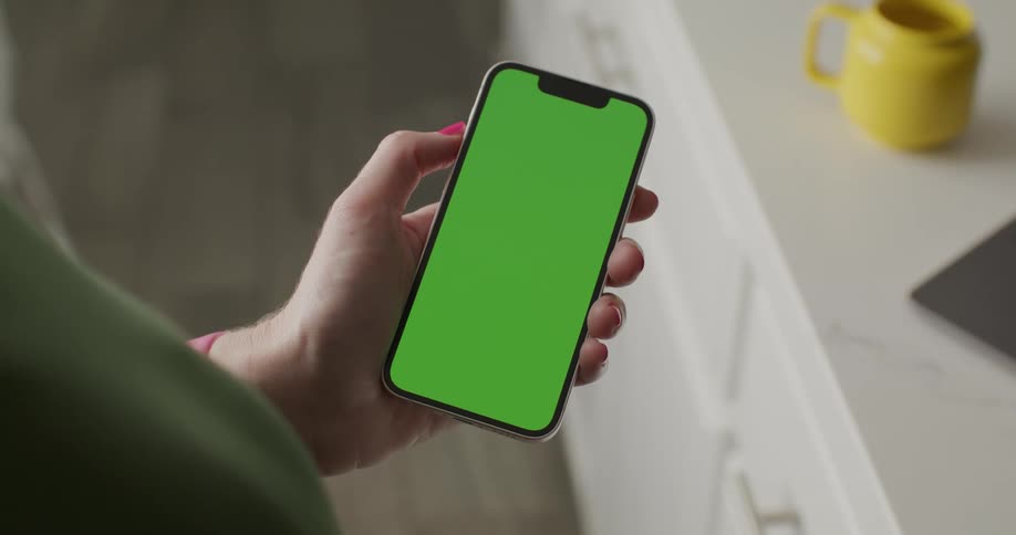 A persons hand holding a cell phone with the screen all green