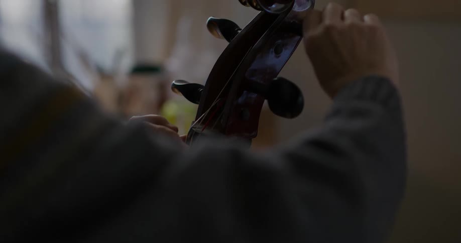 A person tuning the strings of a cello