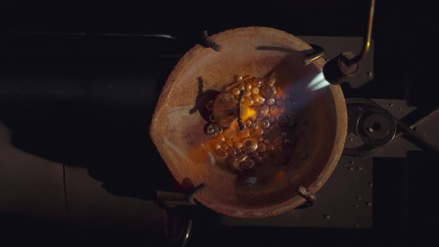 A blowtorch being used to melt objects in a large basin