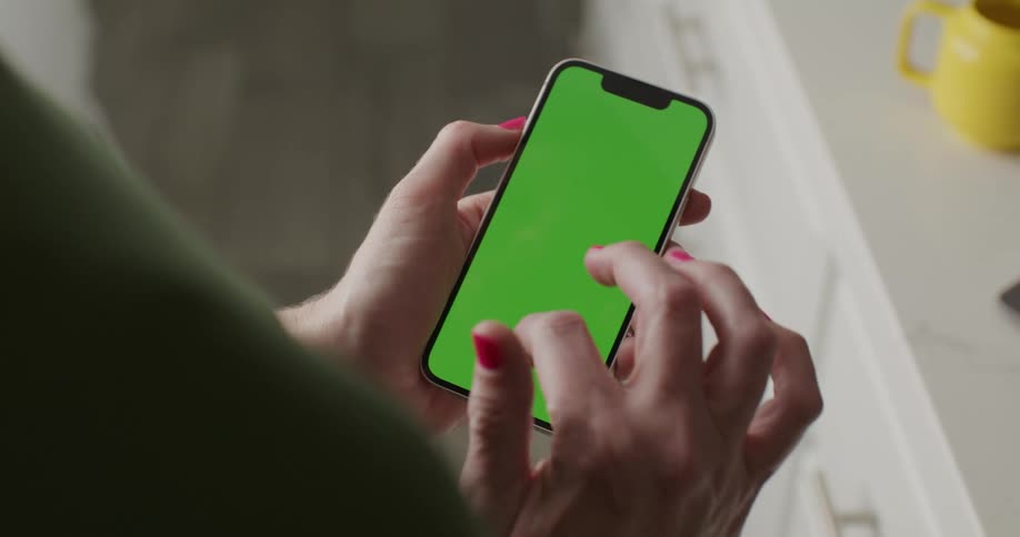 A person holding a smartphone with a green screen