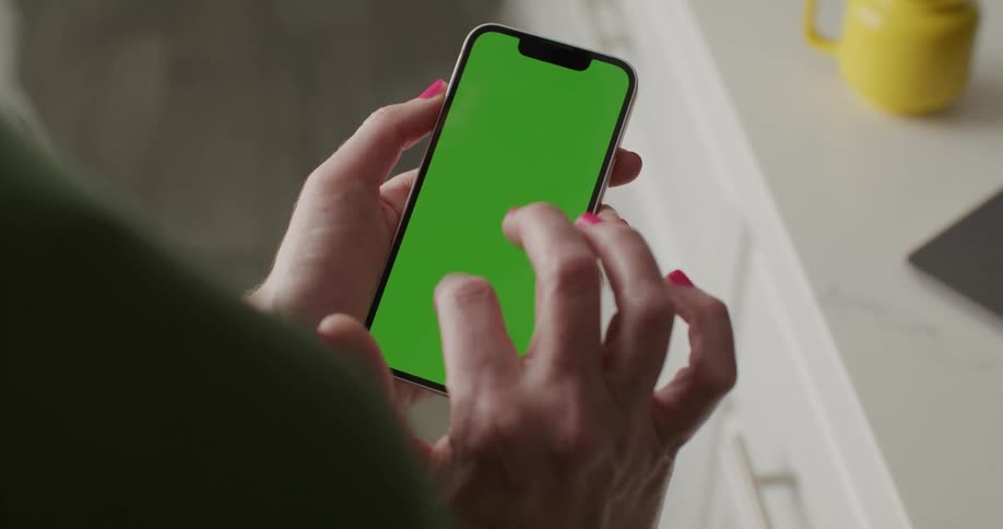 Woman swipes up on her smart phone in her kitchen