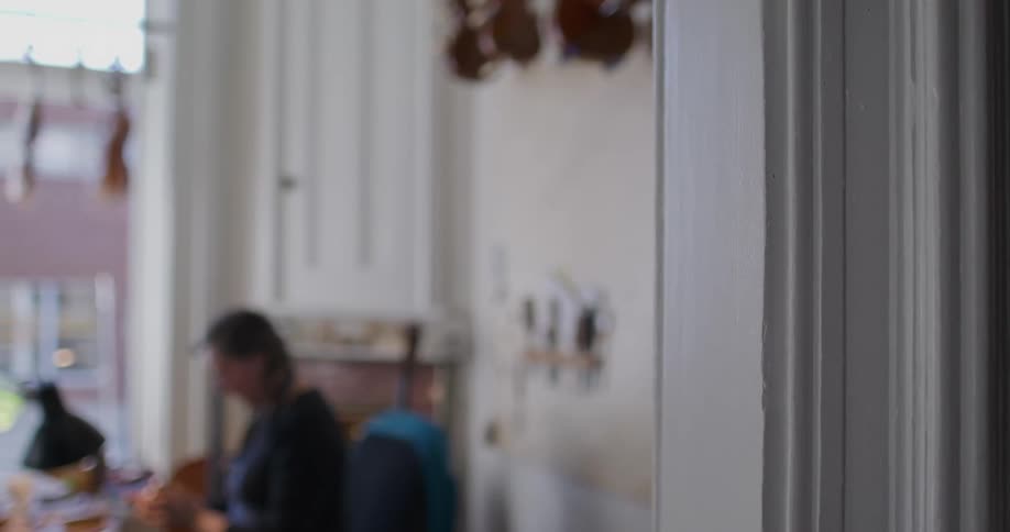 A woman sitting by a window and erasing something from a notepad