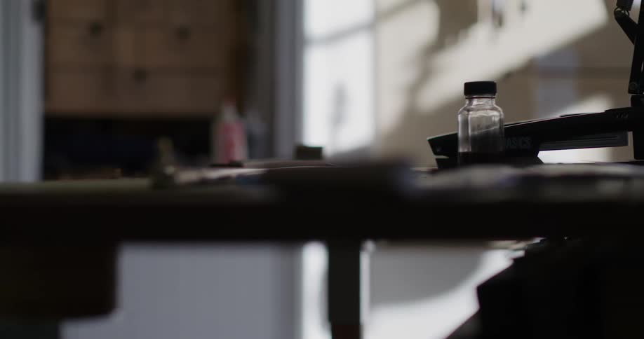 A wooden table has a small bottle and an adjustable lamp atop it