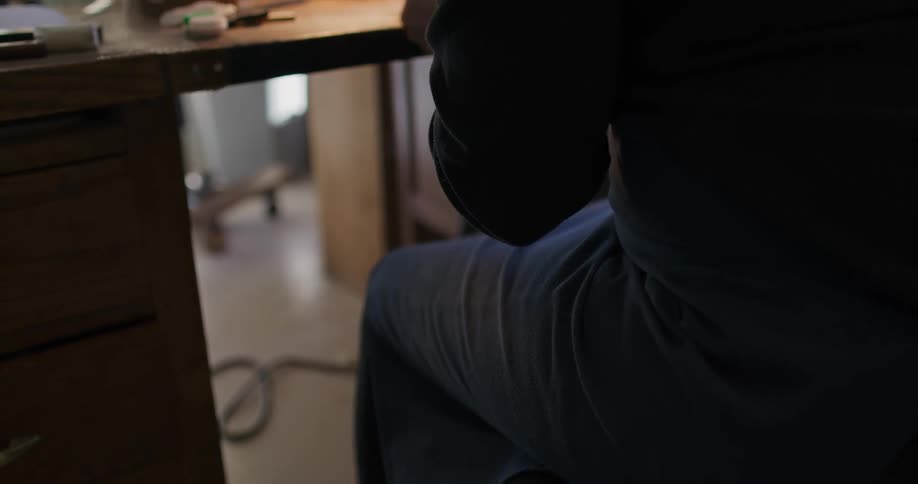 A female sits at a desk where shes assembling a violin