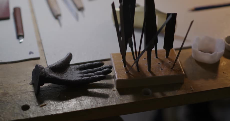 A wooden table with various tools and a black glove