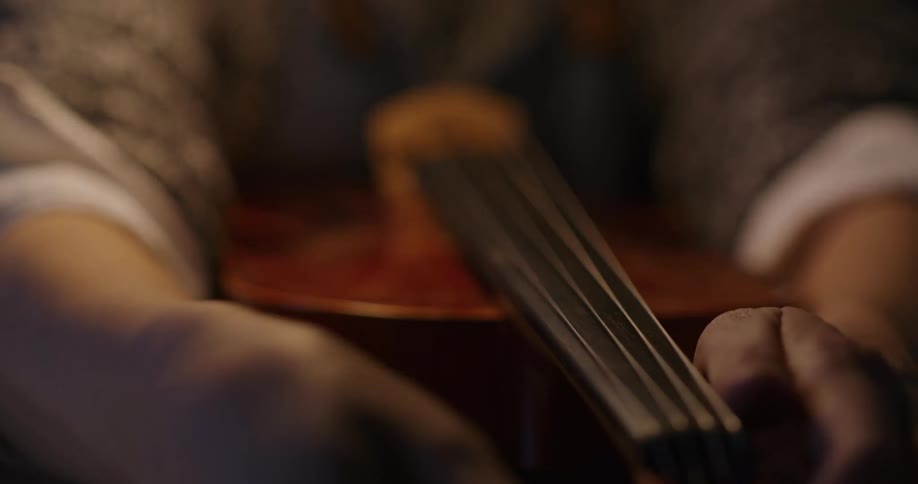 A person is adjusting the strings of a violin that is on a table