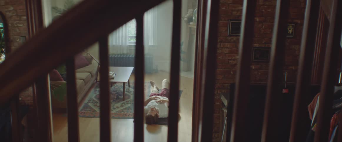 Man with a beard and a white undershirt does crunches in the living room at home
