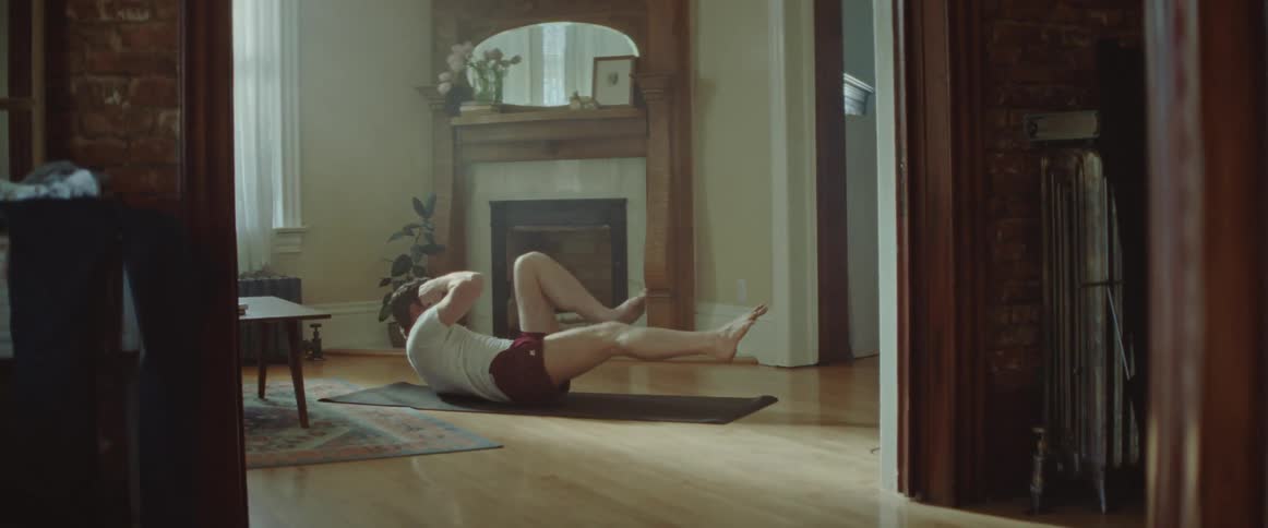 Man does crunches on a pilates mat in the living room at home