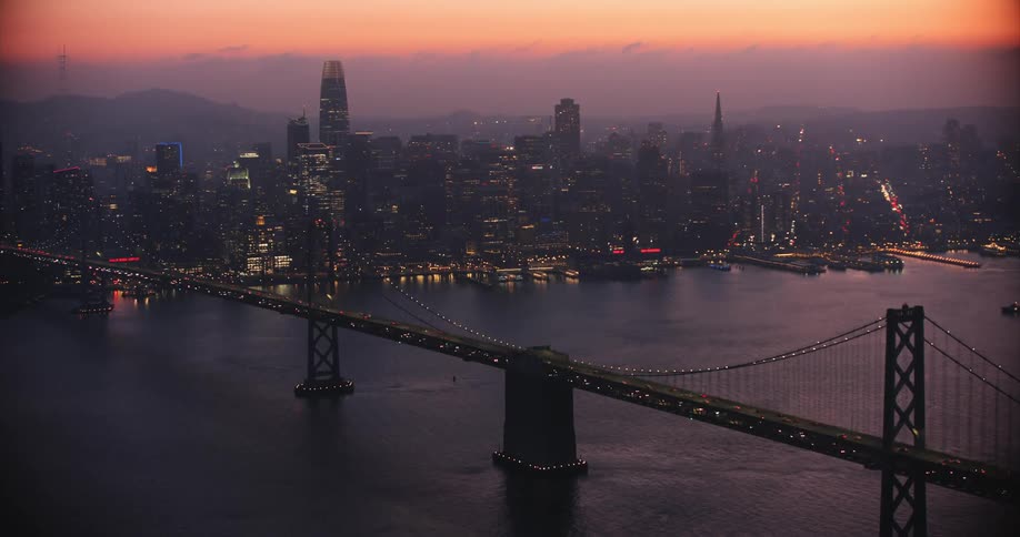 Aerial of the Bay Bridge over the San Francisco Bay in a city at sunset