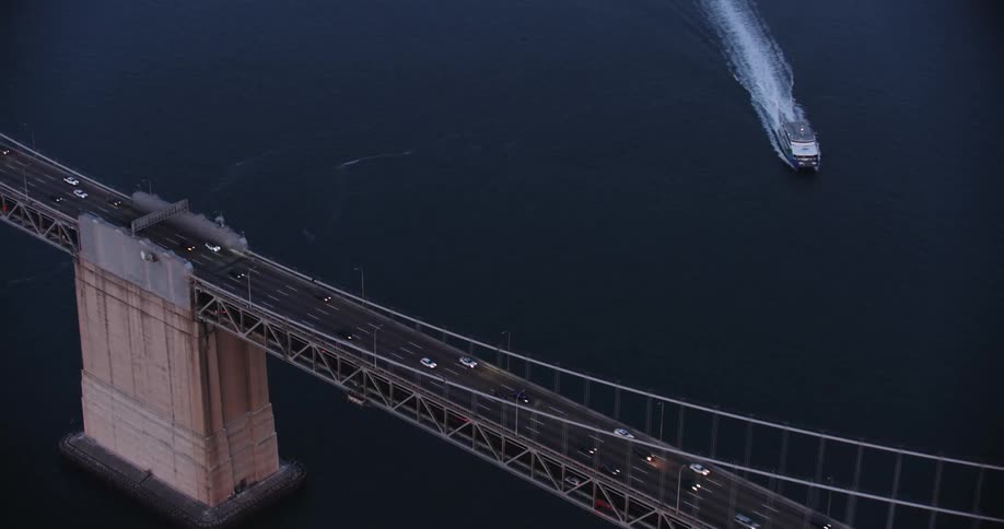 Aerial view of cars driving over the San Francisco Bay Bridge and boat with wake