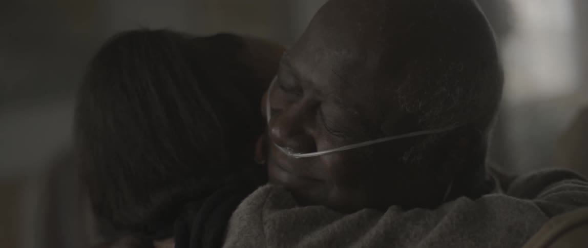 A man reads a card and hugs someone