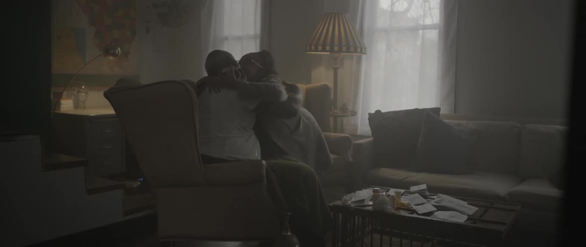 A woman and man look at something together in a living room