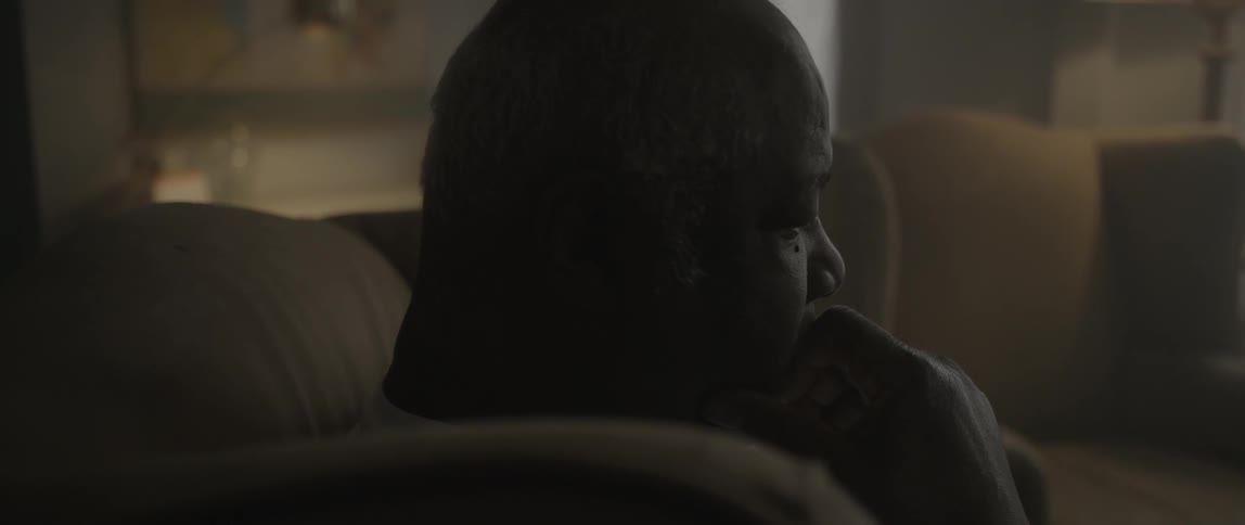 A man is sitting with his hand to his face