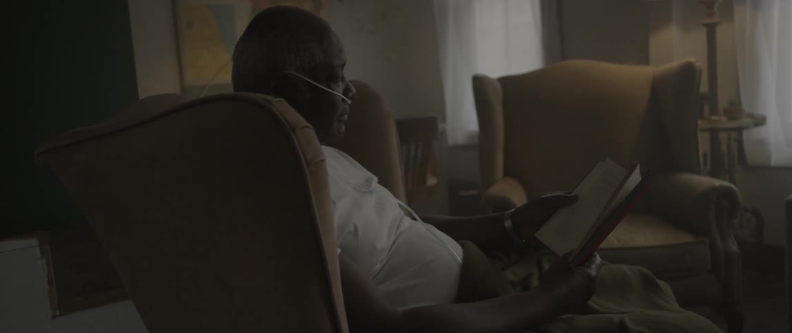 A man is reading a book sitting in his living room