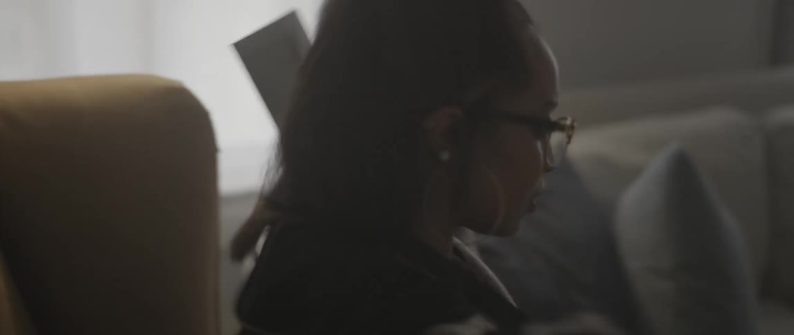 A woman walks into a living room and sits down to talk