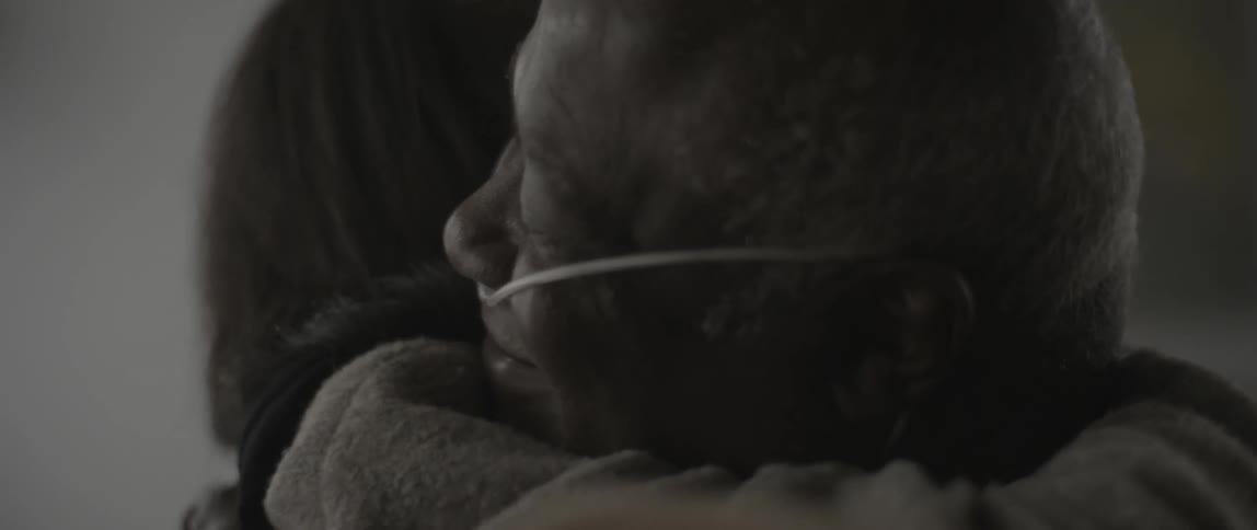 Woman hugs an elderly man with an oxygen tube