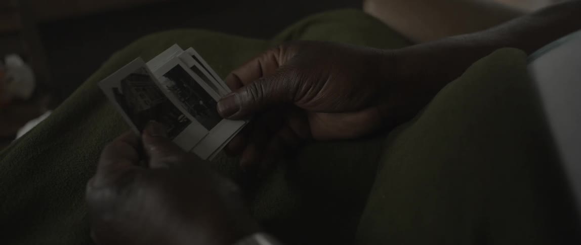 A black woman looks through small photographs