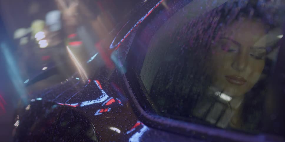 A woman sits in the backseat of a car as the rain pours