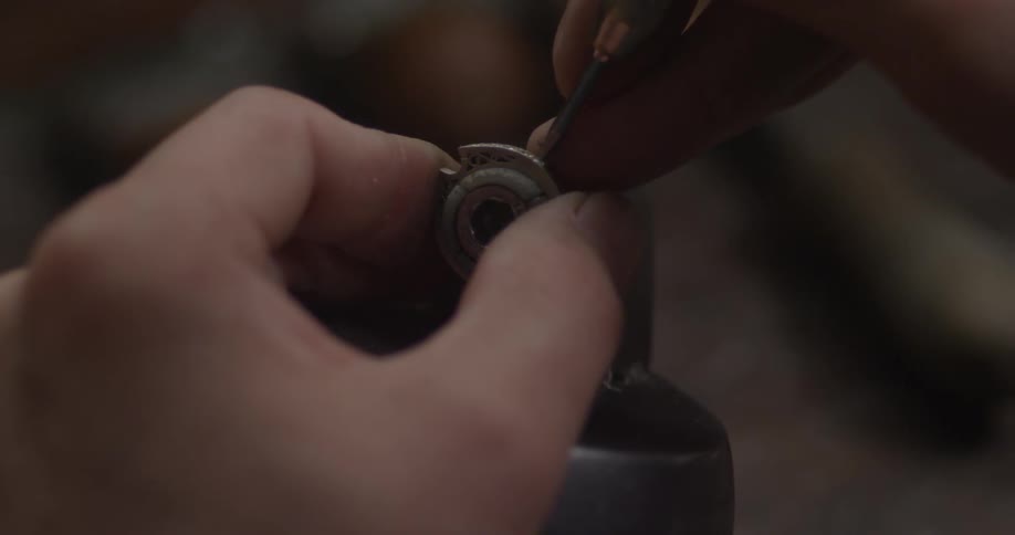 A person uses a tool to set small gems into a ring
