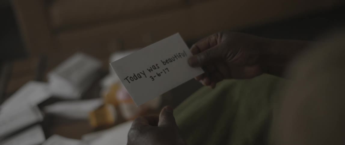 A woman smiling as she hands an envelope of photographs to a man