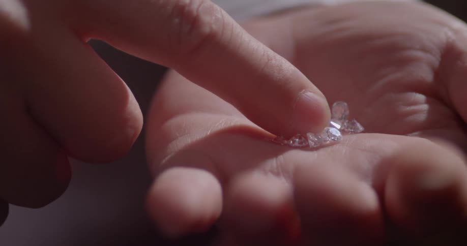 A finger spreads diamonds in the palm of a hand