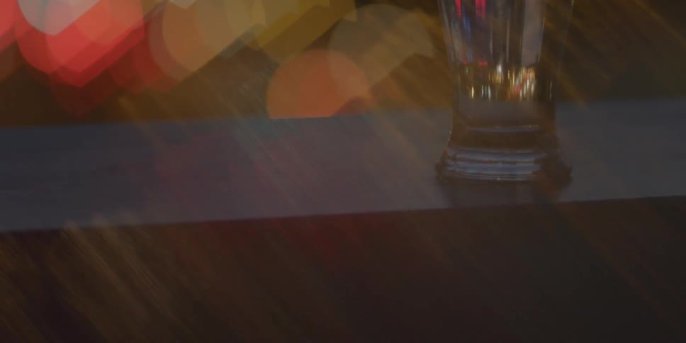 Colored lights move behind a glass sitting on a table