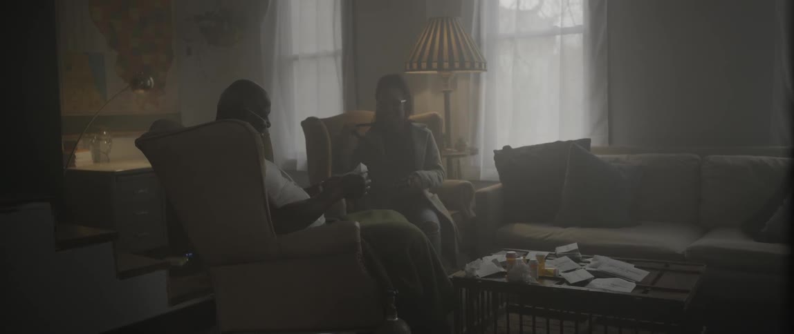 Woman wakes man sleeping in chair to give him a package