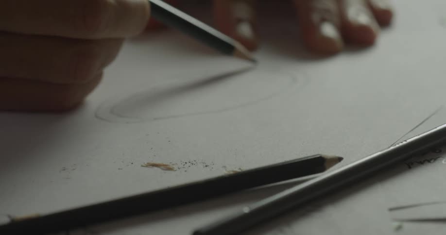 A person draws a circle on a piece of paper with a pencil