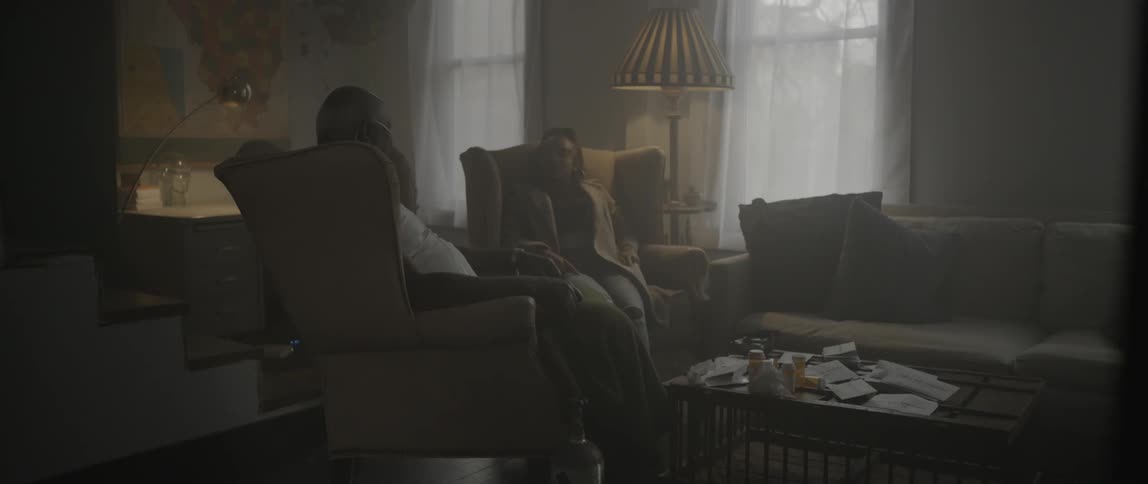 A man and a woman sit in a living room and chat