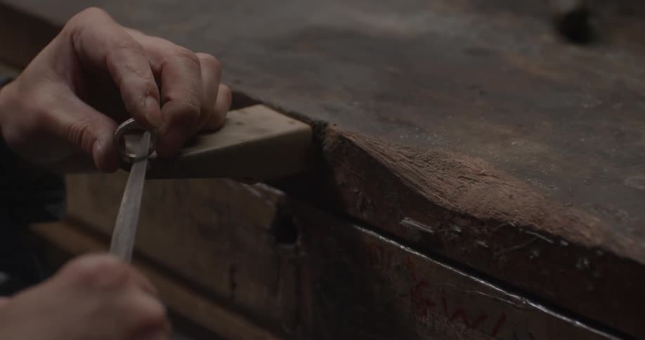 A person rubs a knife on the inside of a metal ring